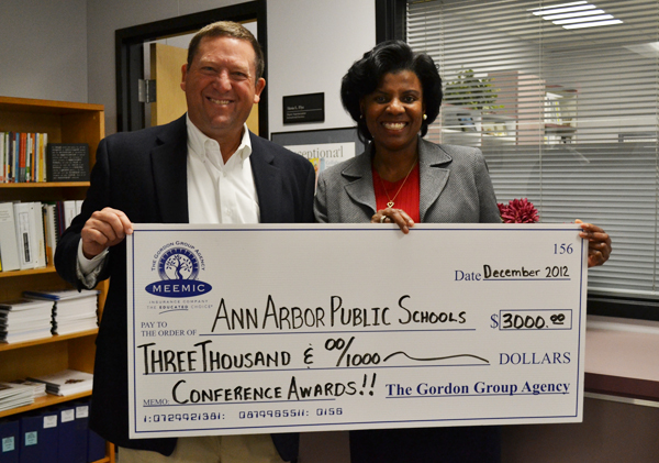 Stew Gordon, president of the Gordon Group Insurance Agency, presents a check to Deputy Superintendent for Instruction Alesia Flye.