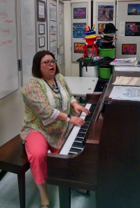Dianna Hochella plays the piano and sings as her students rehearse for an upcoming concert.