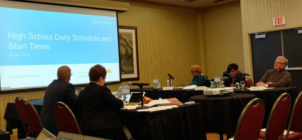 The AAPS BOE Performance committee in a hotel meeting room with a screen in the background highlighting high school start times as the topic of the meeting.