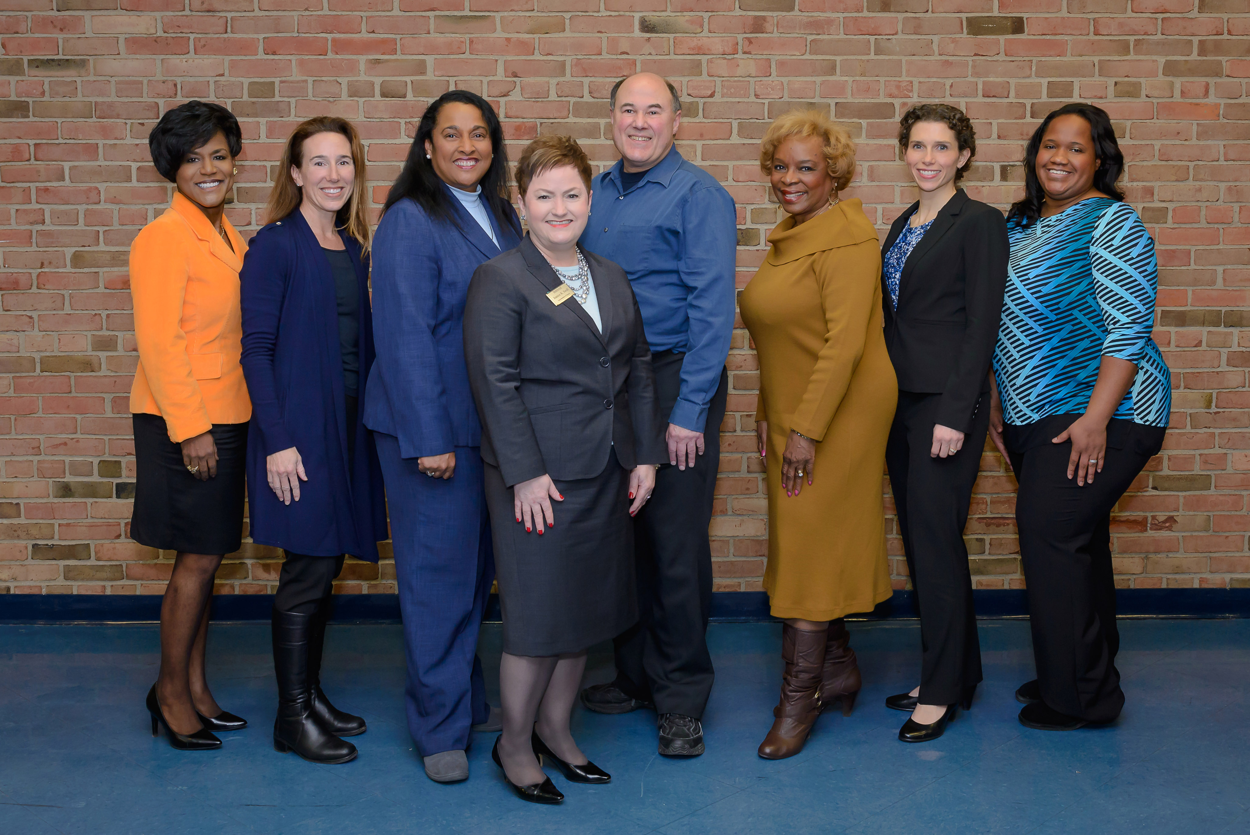 The seven members of the AAPS Board of Education and Superintendent Jeanice Swift stand in front of a brick wall.