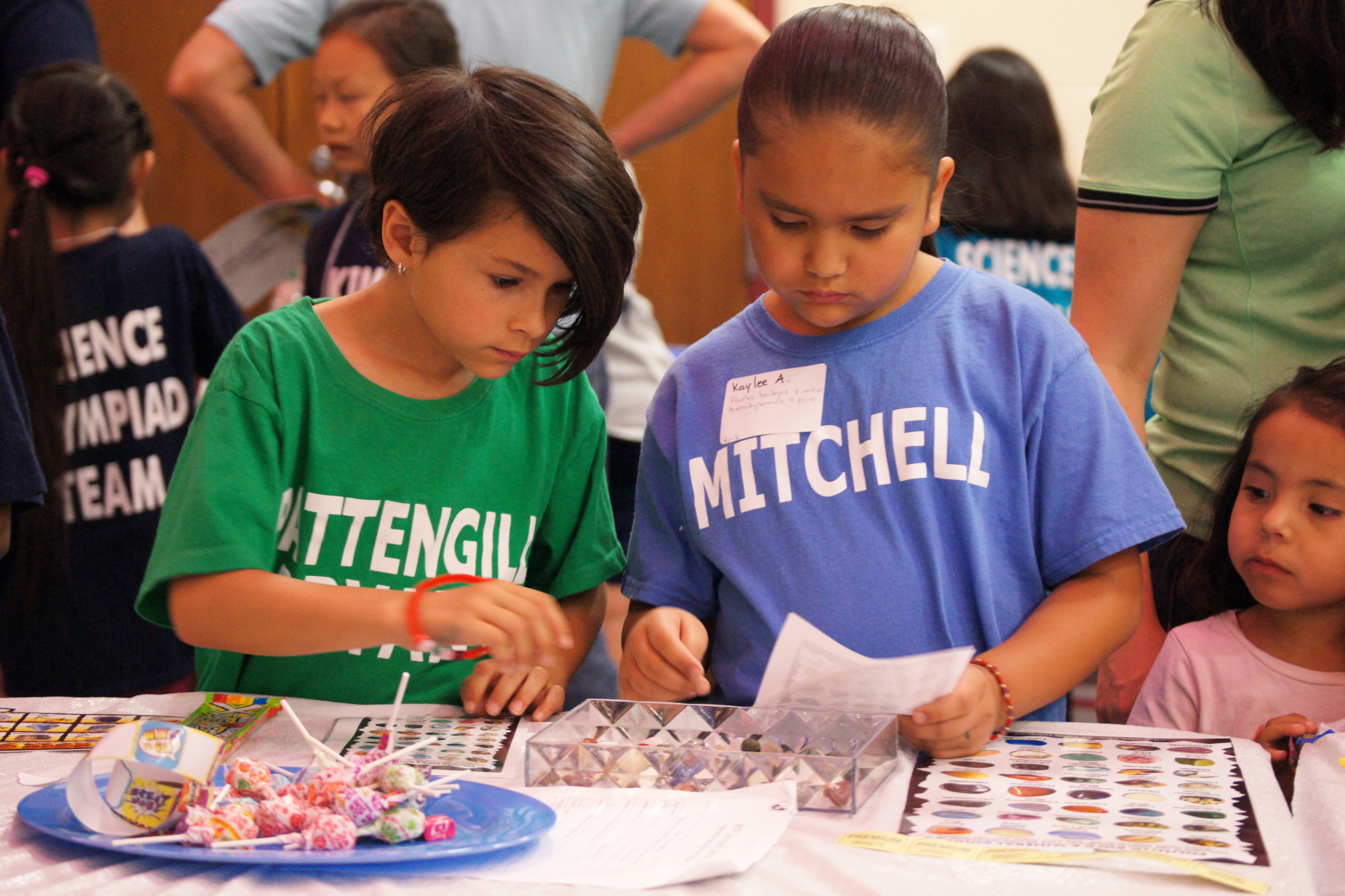 Two second grade students one wearing a green Pattengill Elementary shirt and the other in a light blue Mitchell Elementary shirt