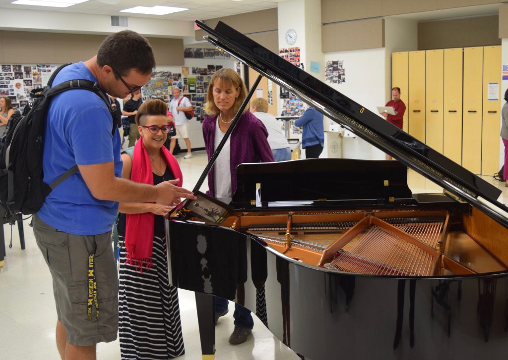 3 AAPS teachers inspect a baby grand piano