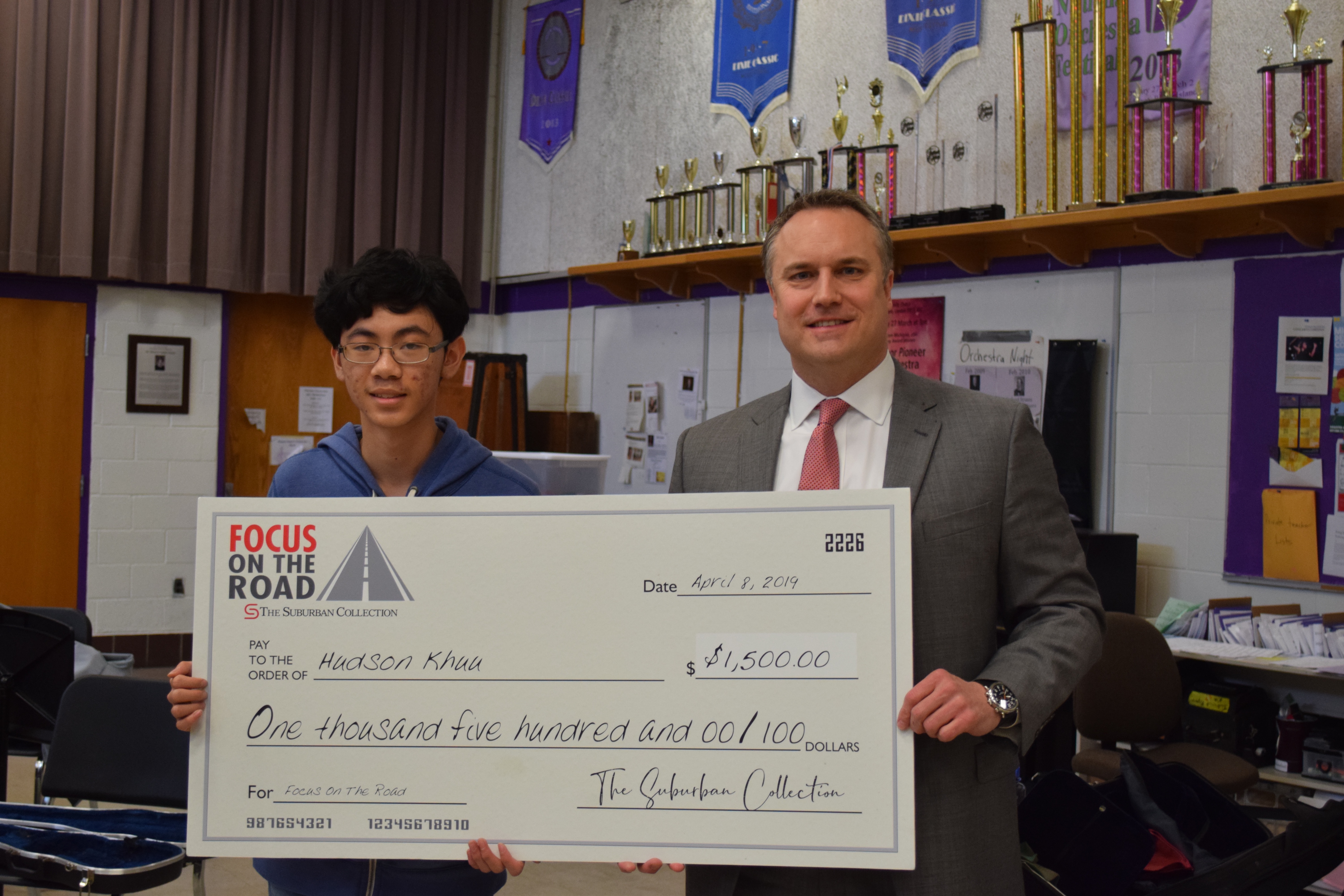 Pioneer 10th grader Brian Khuu holds a giant check for winning the Focus on the Road video competition with the Suburban Collection's Dan Wiebelhaus