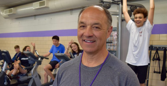 Photo of Coach Steve Rodriquez in the training room with happy students behind him.