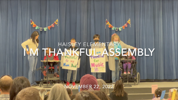 Four students, two in wheel chairs and a pair of adults on stage at Haisley Elementary.