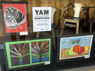 Downtown Ann Arbor storefront window with several pieces of artwork from AAPS students.