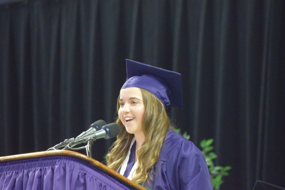 Student Keynote speaker Natalie Walsh in purple cap and gown gives the student keynote address.