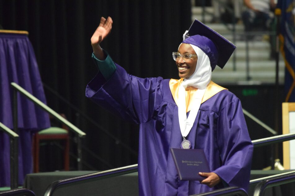 A female Pioneer student waves after receiving her diploma.