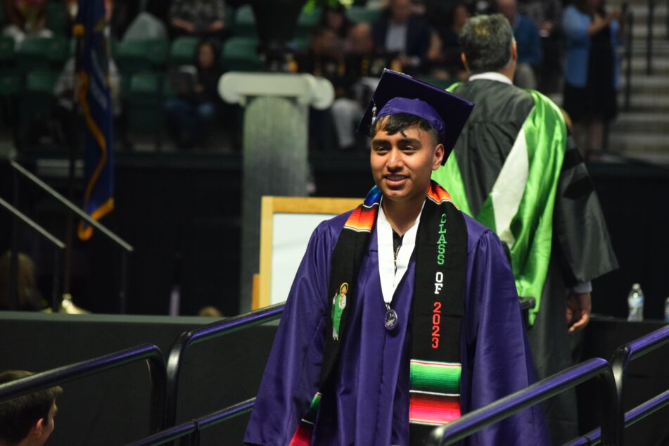 A male Pioneer student crosses the stage after receiving his diploma.