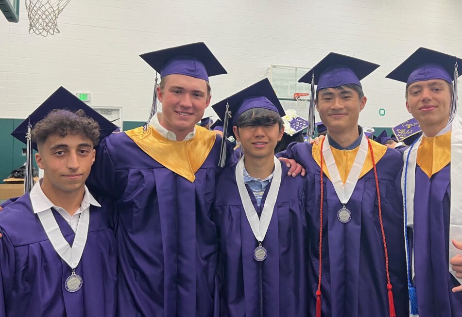 A group of male Pioneer students in caps and gowns before the ceremony begins.
