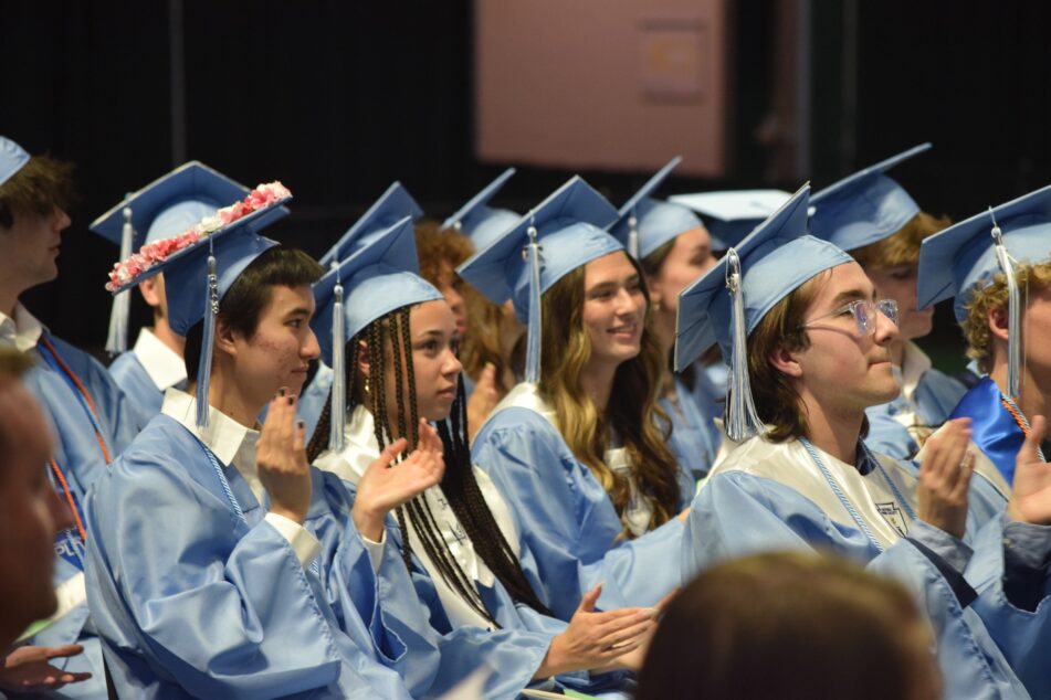 A group of Skyline students in their caps and gowns clap during the Commencement Ceremony.
