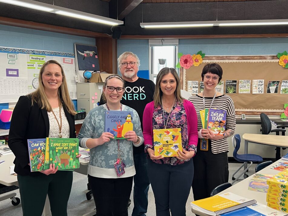 Four Lakewood teachers and former AAPS Trustee Andy Thomas standing in a classroom holding books acquired thanks to a grant from the Karen Thomas Memorial Fund.