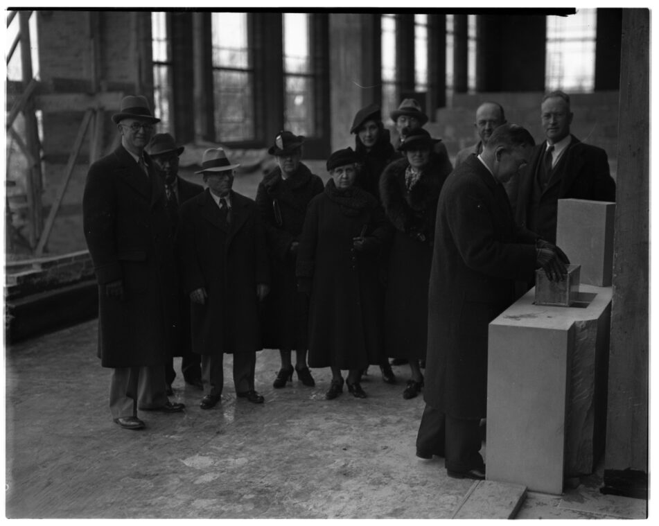 Erich A. Walter, president of the Board of Education, places a sealed box containing numerous bits of data into the cornerstone of the Slauson Junior High School in 1936
