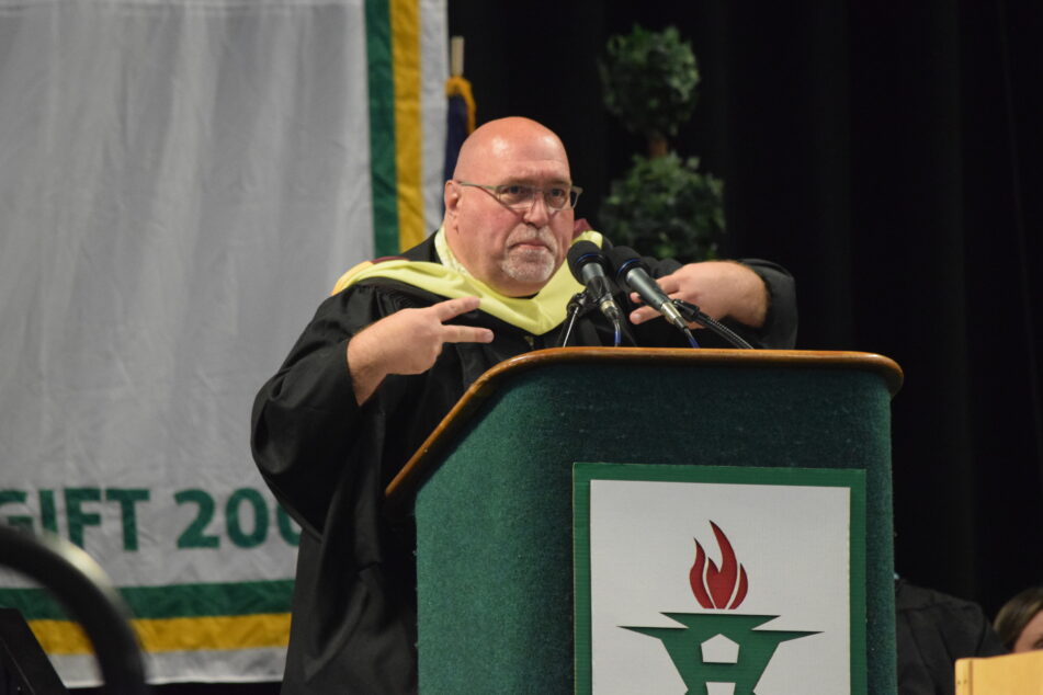 Paraprofessional Bruce Popejoy giving Commencement Address at a podium.