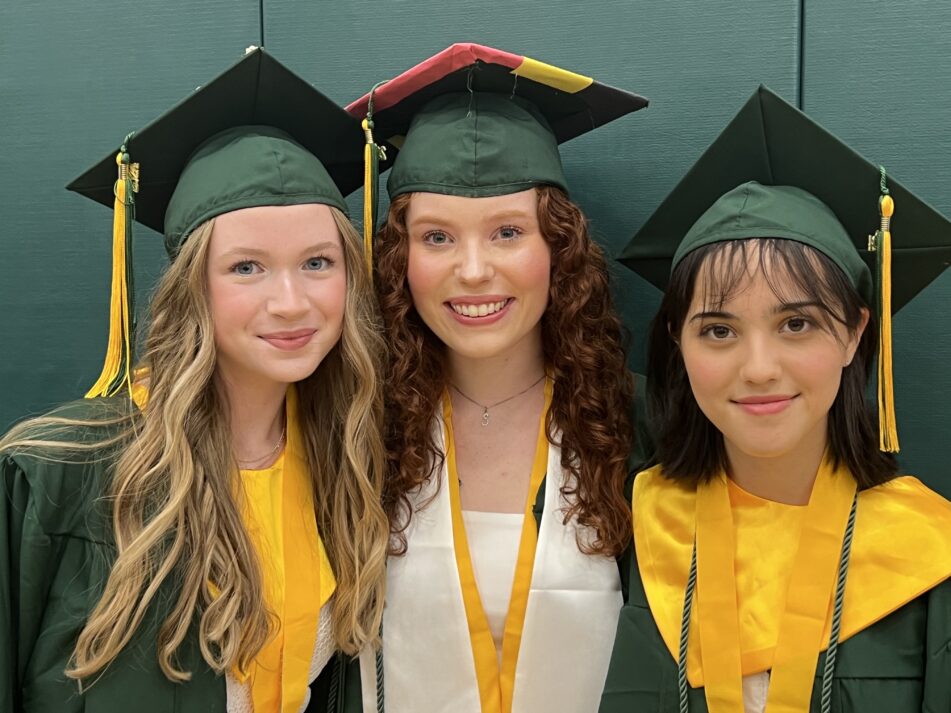 Three female Huron grads before the ceremony in their caps and gowns.