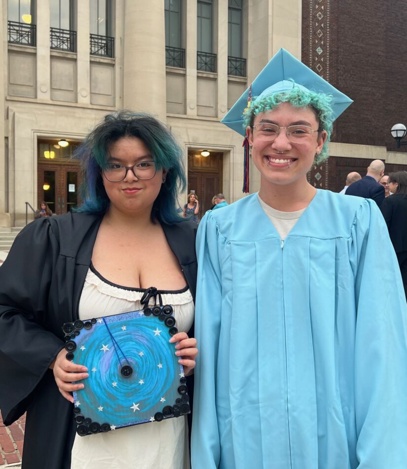 Two Community grads in caps and gowns outside before the ceremony.