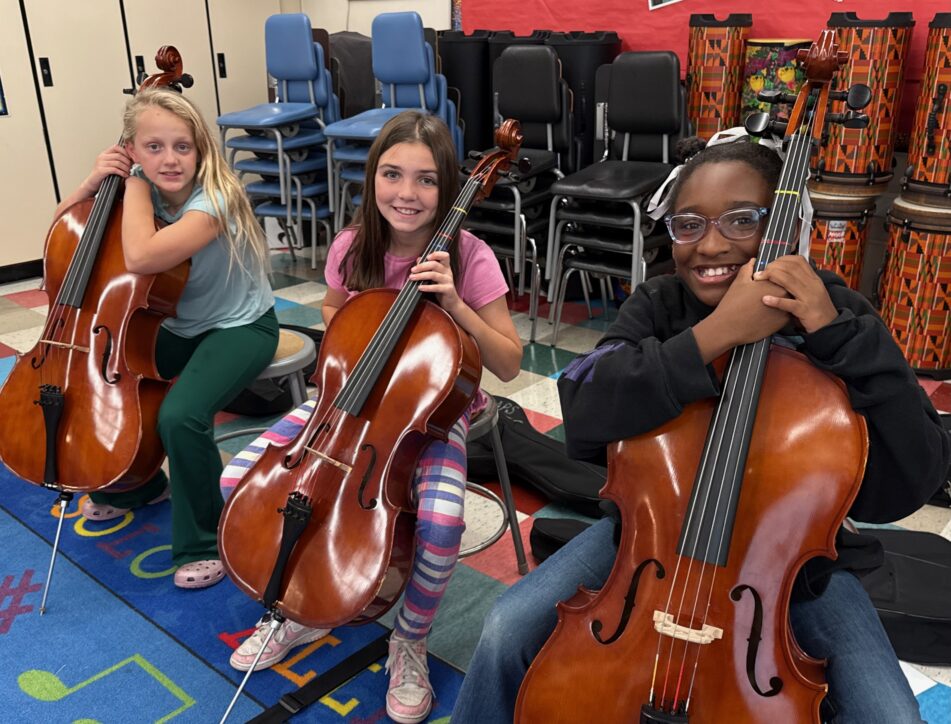 Three Angell students smile while holding upright basses