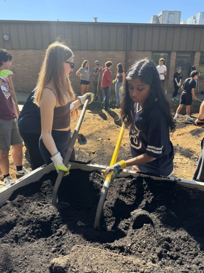 Two female Huron volunteers with shovels in dirt