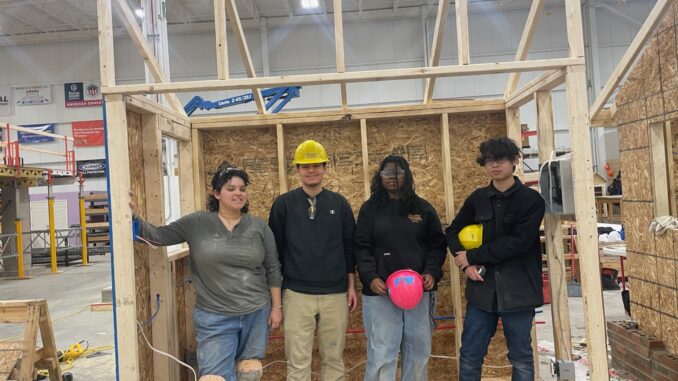 Four homebuilding students inside the structure they built together to demonstrate their skills and ability to work as a team.