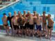 Pioneer Boys Swim and Dive team hold the state championship trophy on the pool deck.