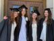 Four Community grads in caps and gowns outside before the ceremony.