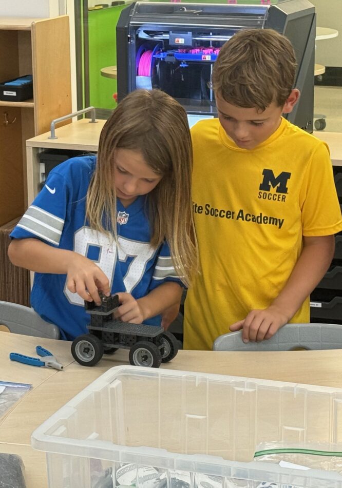 A pair of Wines students assembling a small vehicle in a PLTW class.