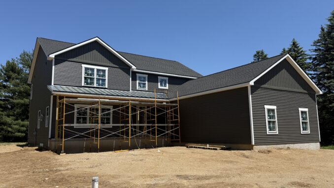 A large house almost finished with some scaffolding still in front and the yard is still dirt