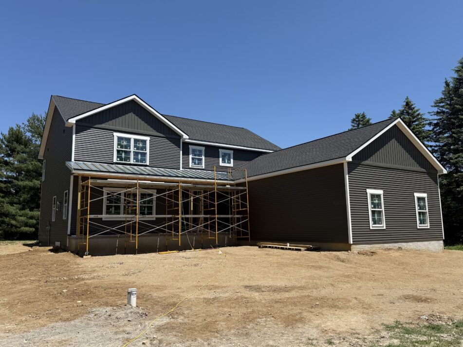 A large house almost finished with some scaffolding still in front and the yard is still dirt