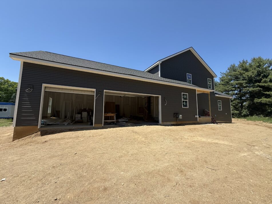 A large nearly finished house on a dirt yard that doesn't yet have a driveway or landscaping.